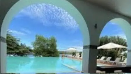 Dès les premières minutes passées à la Maison d’Akoula, les visiteurs sont plongés dans un univers artistique fascinant. Les murs de l’entrée et des couloirs sont ornés de peintures vibrantes, tandis que des sculptures en bois minutieusement travaillées trônent dans les espaces communs. Ces pièces uniques, toutes réalisées par des artistes locaux, racontent l’histoire et les traditions des différentes régions de Côte d’Ivoire. Chaque chambre de ce palace porte le nom d’une région ivoirienne, et sa décoration intérieure s’inspire des caractéristiques culturelles de cette région. Par exemple, une chambre dédiée au peuple Akan peut présenter des tissus traditionnels Kente, tandis qu’une autre, inspirée des peuples de l’Ouest, expose des masques et des statuettes Guéré. Ces éléments immersifs transforment le séjour en une véritable exploration culturelle.