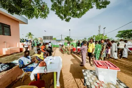 À Gogounou, dans le département de l’Alibori, les cours d’écoles ont connu leur plus forte affluence aux toutes premières heures de la matinée. Dans cette région septentrionale où le pastoralisme rythme le quotidien, l’objectif premier des habitants était de devancer la montée des températures. « Je suis venu m’aligner depuis 6h30. Avec le soleil qui frappe vite ici, il vaut mieux voter à la fraîche. Comme il n’y a pas d’activité au champ aujourd’hui, je vais juste rentrer m’occuper de mes bêtes à la maison », explique Orou, éleveur, l’index marqué par l’encre indélébile.