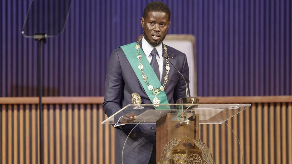 Le plus jeune Président du Sénégal prête serment devant ses pairs africains Les dernières élections du 24 Mars 2024 en République du Sénégal, qui annoncent une nouvelle vague de changement par les urnes en Afrique, est très singulière d’abord par l’alternance relativement sereine entre le Président Macky Sall et le nouveau locataire du palais présidentiel le Président Bassirou Diomaye Faye ; l’autre singularité des dernières élections au Sénégal ce sont les annonces faites pendant la campagne électorale par le candidat Bassirou Diomaye Faye qui a promis de rétablir la souveraineté de son pays notamment en revisitant l’appartenance à la zone du Franc CFA et en renégociant les contrats pétroliers et gaziers ainsi que les accords de pêche, conclus par le passé.